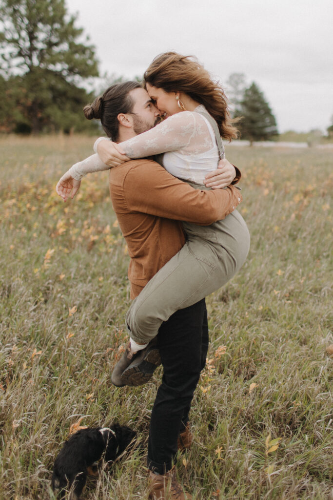 A couple in a prairie grass field taking engagement photos at Holmes Lake in Lincoln Nebraska. 