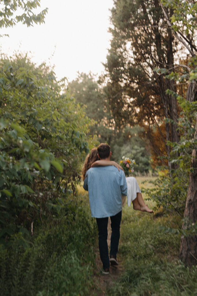 A couple in the woods posing for a photographer at Pioneers Park in Lincoln, Nebraska, during their engagement photo session