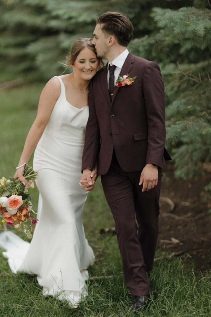 groom kisses brides head as they take portraits at Heartland Country Barn 