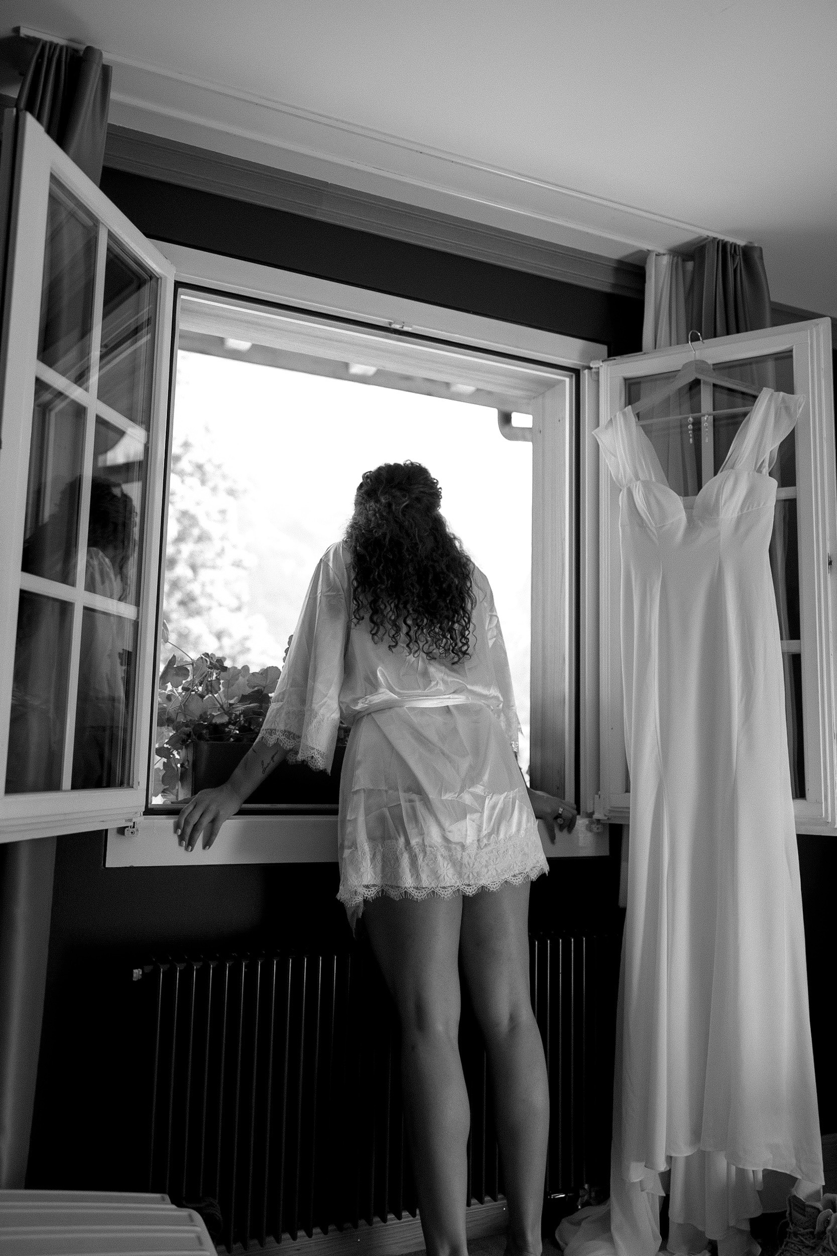 Bride looks out the window of her Switz Alps Airbnb before getting dressed on her wedding day