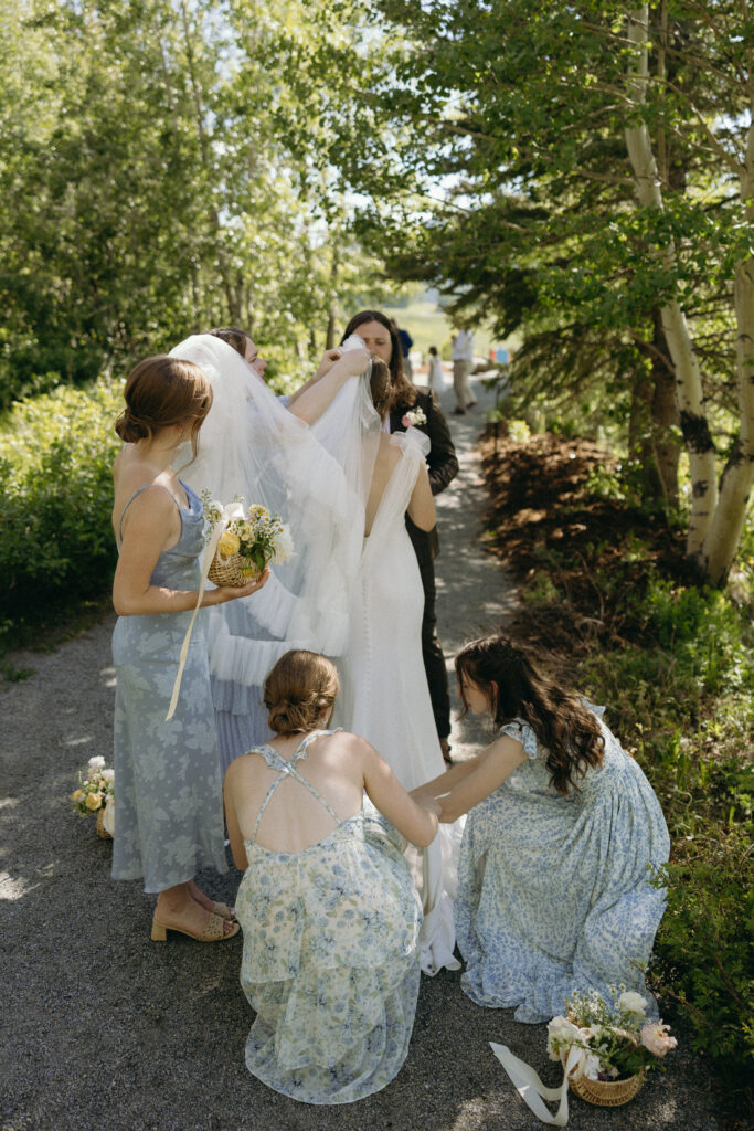 bridesmaids in blue helping to adjust the brides gown