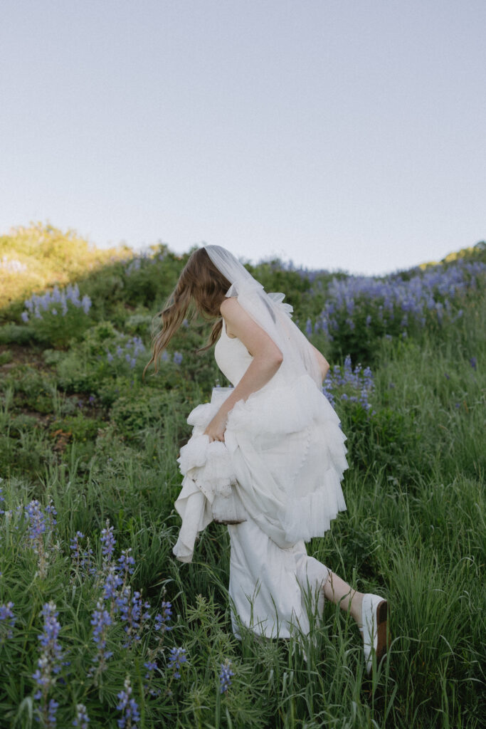 bride runs through a field of wild flowers in crested butte Co