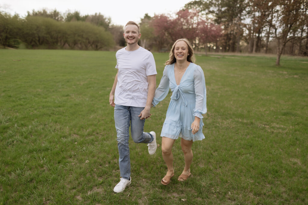couple walks hand in hand through grass field 