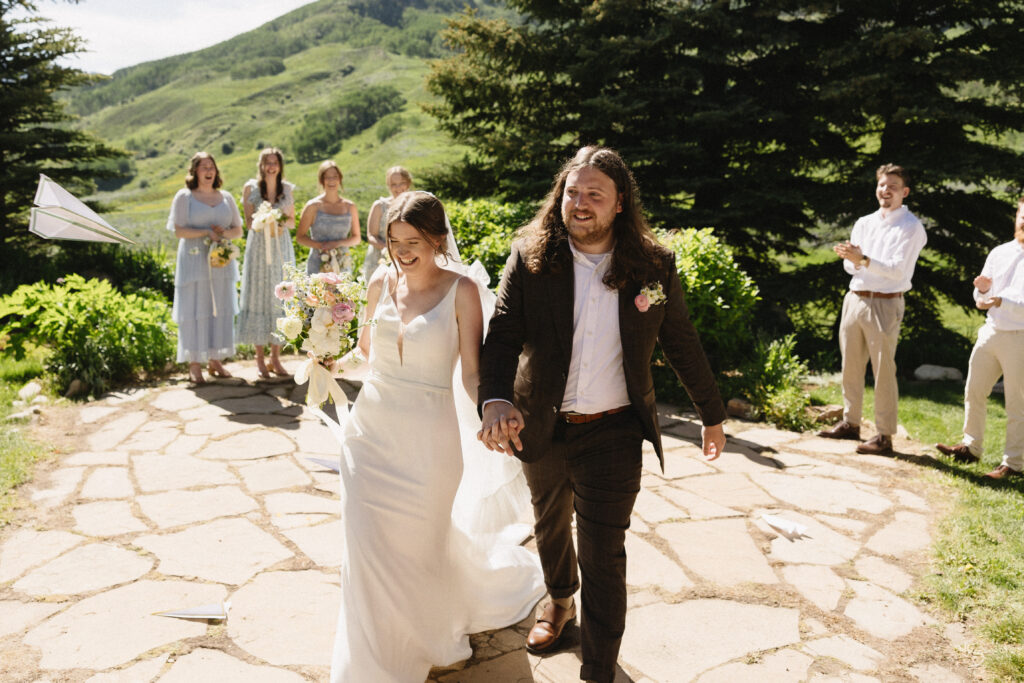 bride and groom walk hand in hand down the aisle after being married