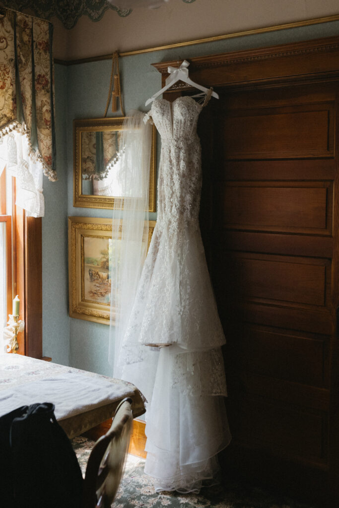 the brides dress hangs in the windo 