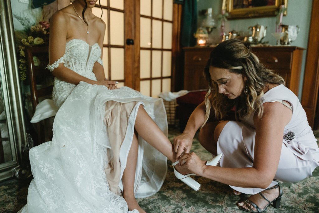 the brides mother helps with her shoes 