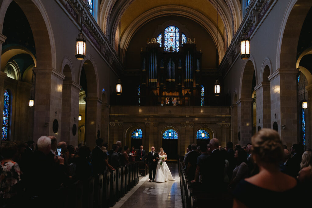 bride walks down the aisle at the St Cecilia's Cathedral in Omaha 