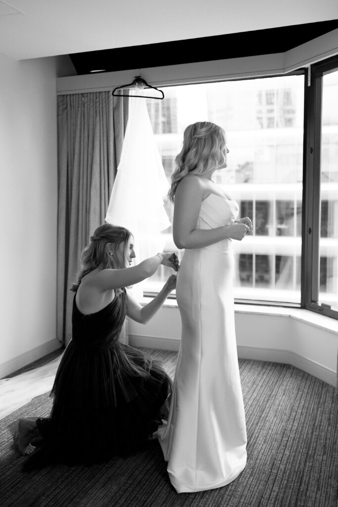bride's sister helps her into her dress