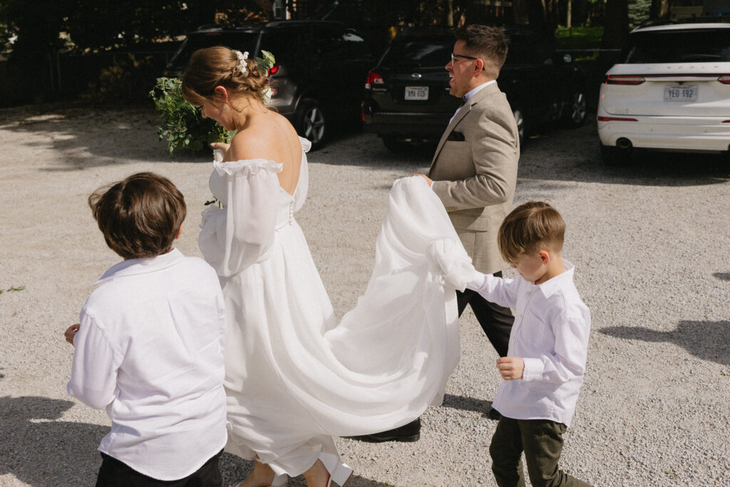 ring bearers help the bride carry her dress 