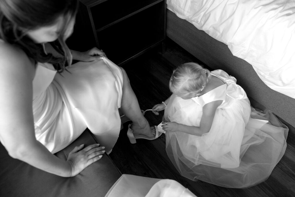 flower girl helps bride put on shoe 