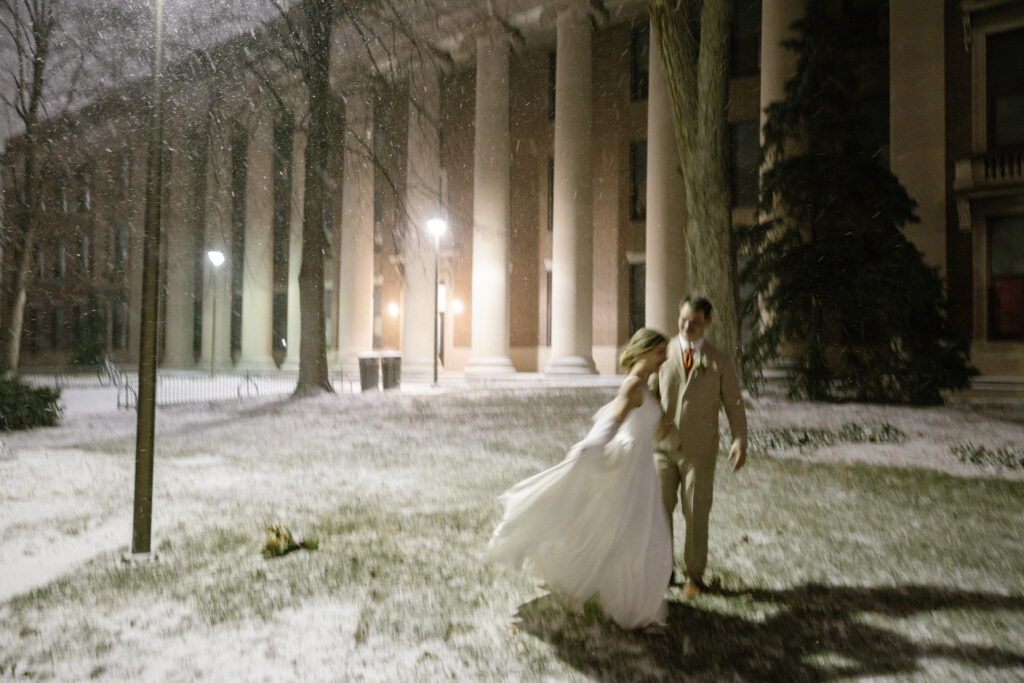 bride and groom take portraits in the falling snow 